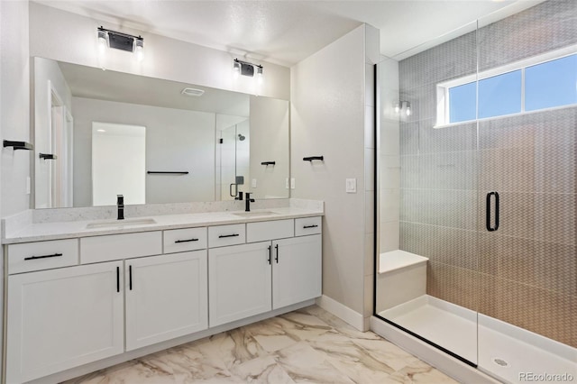 bathroom featuring a stall shower, marble finish floor, a sink, and double vanity