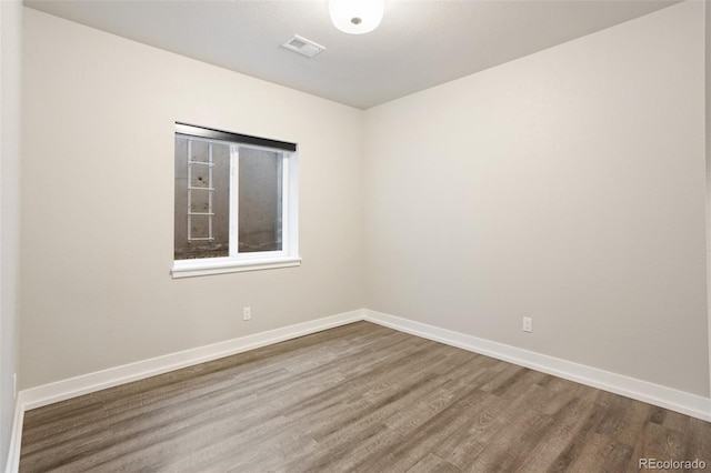 empty room featuring baseboards, visible vents, and wood finished floors