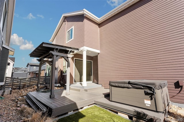 back of house with fence, a wooden deck, and a hot tub