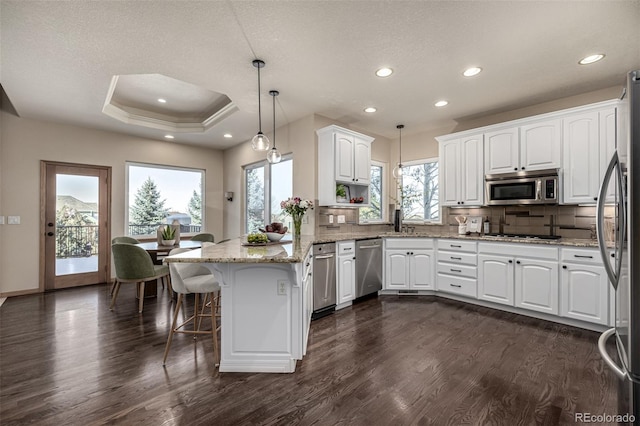 kitchen featuring appliances with stainless steel finishes, decorative light fixtures, and white cabinetry