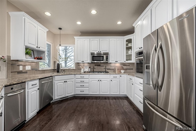 kitchen with decorative backsplash, hanging light fixtures, white cabinets, and stainless steel appliances