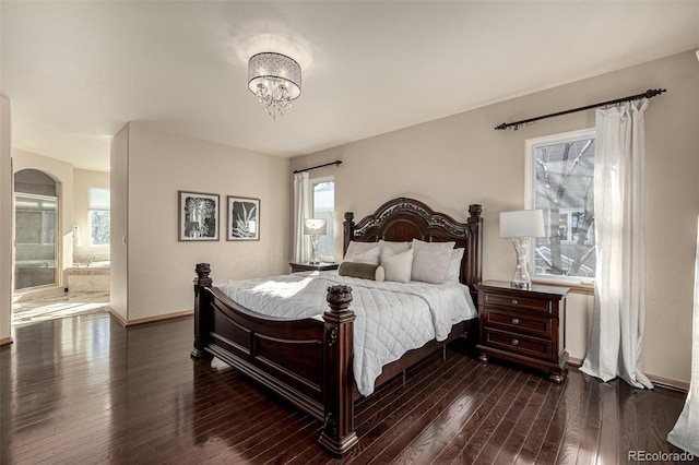 bedroom with ensuite bathroom, dark wood-type flooring, and a notable chandelier