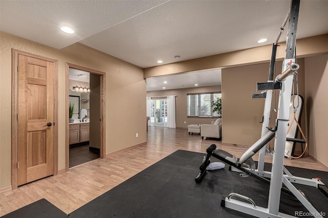 workout area featuring a textured ceiling, hardwood / wood-style flooring, and sink