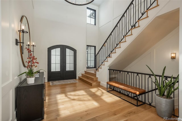 entrance foyer featuring french doors, wood-type flooring, and a high ceiling