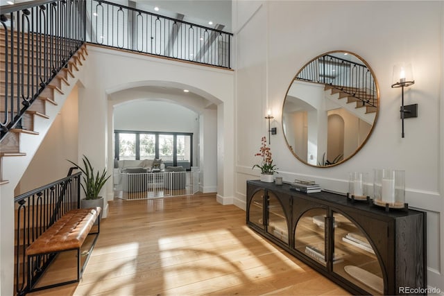 entrance foyer with light hardwood / wood-style floors and a towering ceiling