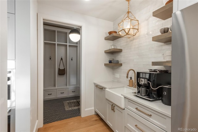 mudroom with an inviting chandelier, sink, and light hardwood / wood-style floors