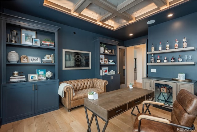 office area featuring beverage cooler, built in shelves, coffered ceiling, beamed ceiling, and light wood-type flooring