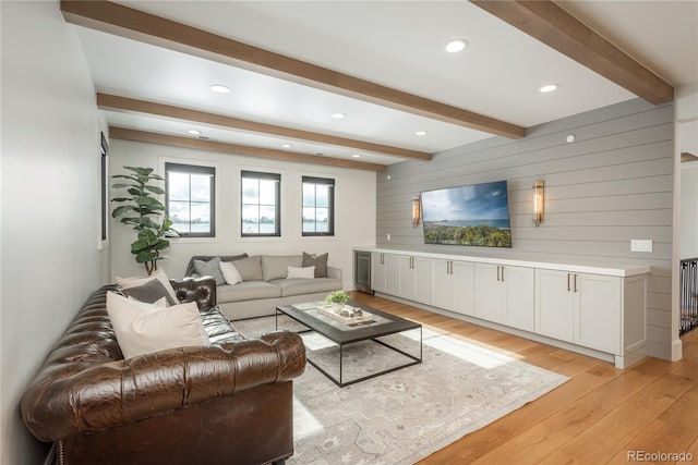 living room featuring light hardwood / wood-style floors, wooden walls, and beamed ceiling