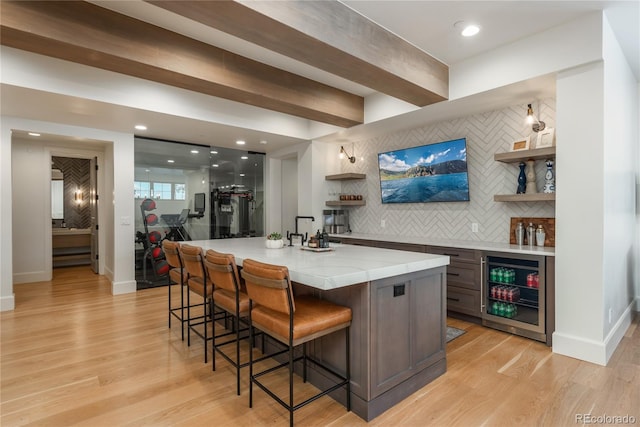 bar featuring decorative backsplash, light hardwood / wood-style flooring, and beverage cooler