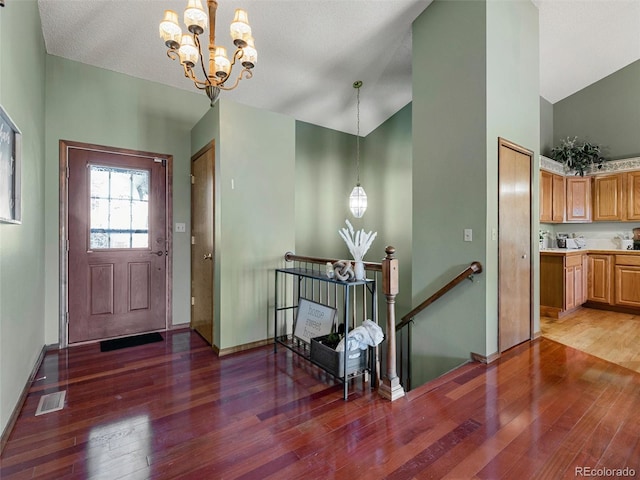 entryway featuring a notable chandelier, visible vents, high vaulted ceiling, light wood-type flooring, and baseboards