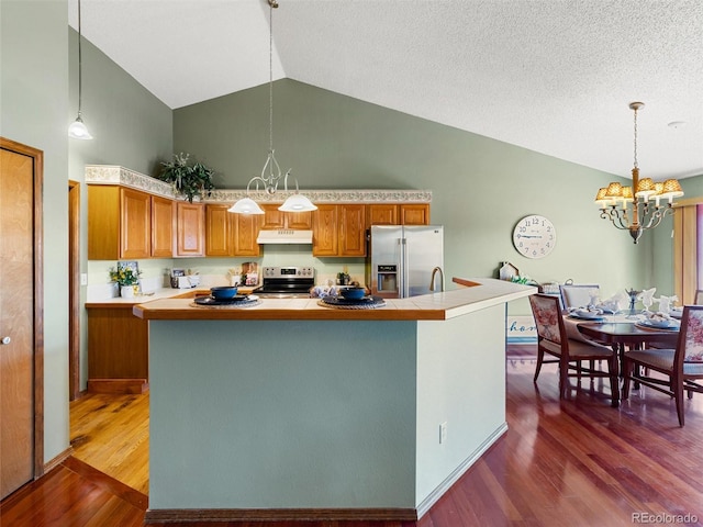 kitchen with stainless steel appliances, brown cabinets, dark wood-type flooring, and under cabinet range hood