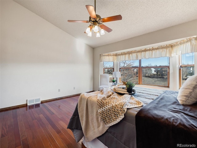 bedroom featuring lofted ceiling, visible vents, a textured ceiling, baseboards, and hardwood / wood-style flooring