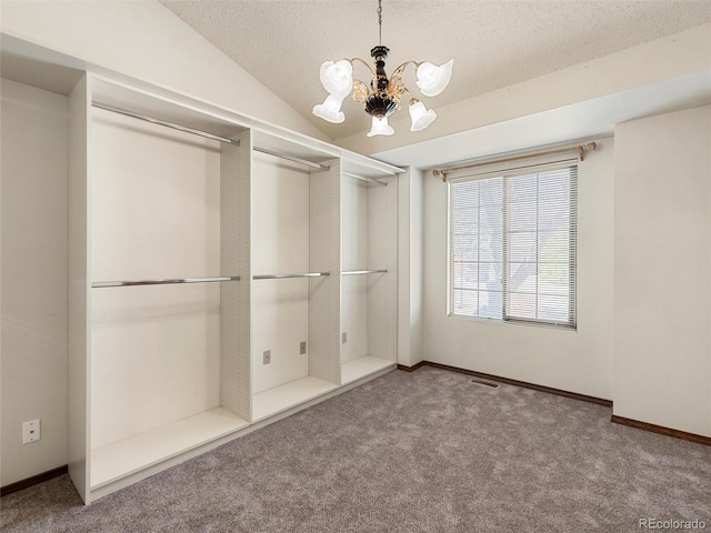 unfurnished bedroom featuring carpet floors, visible vents, an inviting chandelier, vaulted ceiling, and a textured ceiling