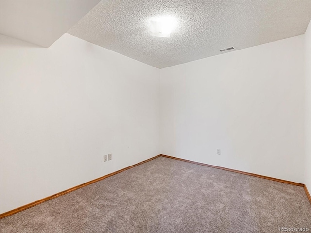 carpeted empty room featuring visible vents, baseboards, and a textured ceiling