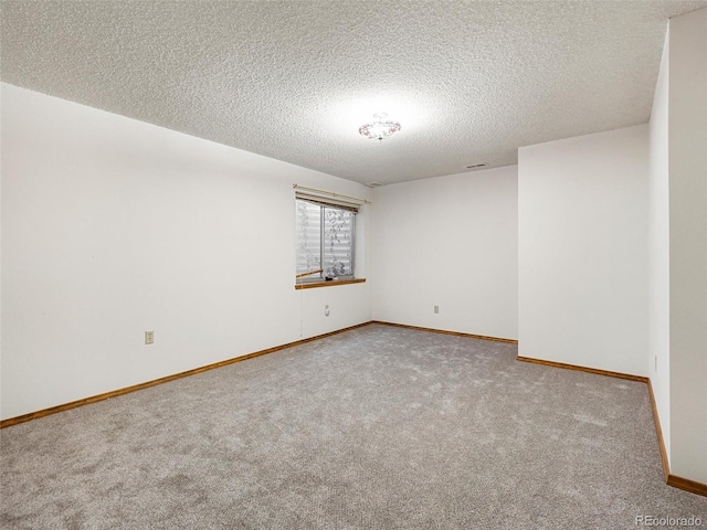 carpeted spare room with visible vents, a textured ceiling, and baseboards