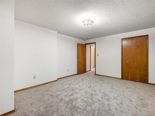 empty room with carpet floors, a textured ceiling, and baseboards