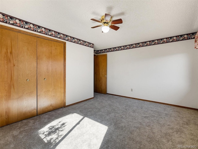 unfurnished bedroom featuring a closet, a ceiling fan, carpet flooring, a textured ceiling, and baseboards