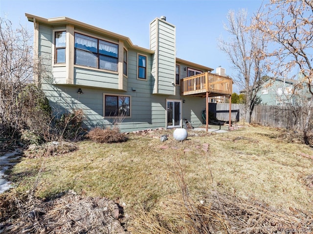 back of property with a chimney, fence, a deck, and a yard