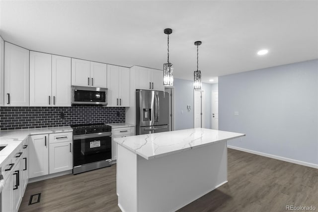 kitchen featuring dark wood-style floors, a center island, decorative backsplash, appliances with stainless steel finishes, and white cabinetry