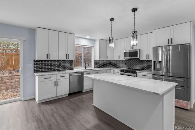 kitchen featuring decorative backsplash, dark wood finished floors, a kitchen island, appliances with stainless steel finishes, and a sink