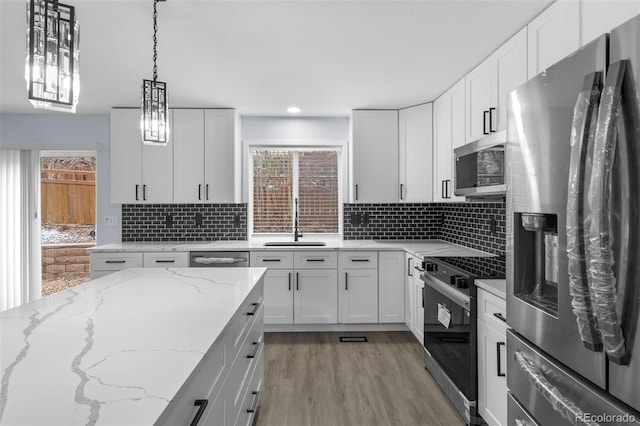 kitchen with appliances with stainless steel finishes, white cabinetry, a sink, and tasteful backsplash