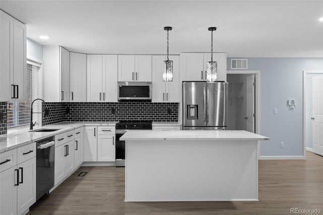 kitchen with stainless steel appliances, a sink, visible vents, and decorative backsplash