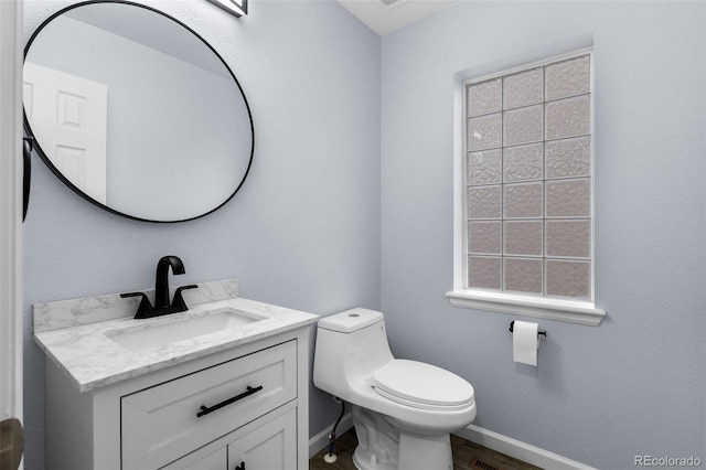 bathroom with toilet, wood finished floors, vanity, and baseboards