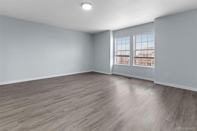 unfurnished room with visible vents, baseboards, and wood finished floors