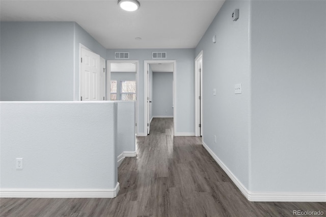 hall featuring baseboards, visible vents, and wood finished floors