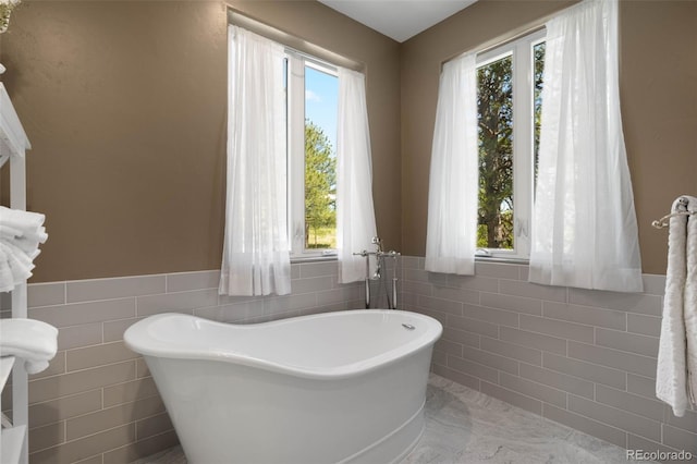 10914 Remmick Ridge Rd, Parker, CO 80134 - bathroom featuring tile walls, a soaking tub, plenty of natural light, and wainscoting
