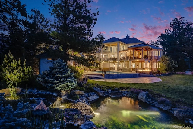 10914 Remmick Ridge Rd, Parker, CO 80134 - back of property at dusk featuring a balcony, an outdoor pool, a yard, and a small pond