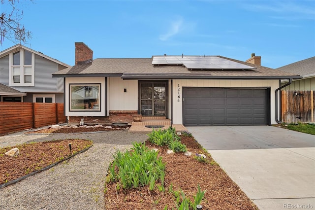 12164 E Amherst Cir, Aurora, CO 80014 - view of front of home with an attached garage, roof mounted solar panels, a chimney, fence, and concrete driveway
