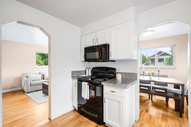 2255 Perry St, Denver, CO 80212 - kitchen featuring black appliances, arched walkways, light wood-style floors, white cabinets, and baseboards