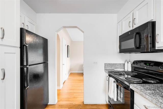 2255 Perry St, Denver, CO 80212 - kitchen with black appliances, arched walkways, white cabinetry, and light wood-style floors