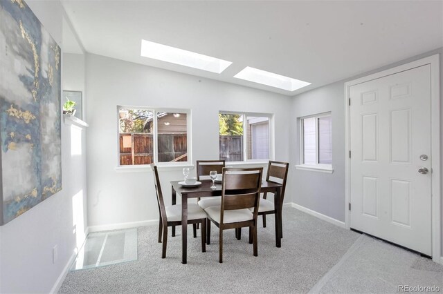 carpeted dining room with vaulted ceiling and baseboards