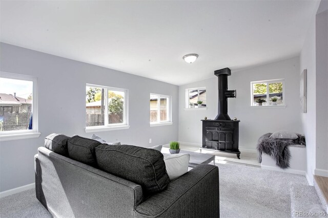 carpeted living area with a wood stove and baseboards