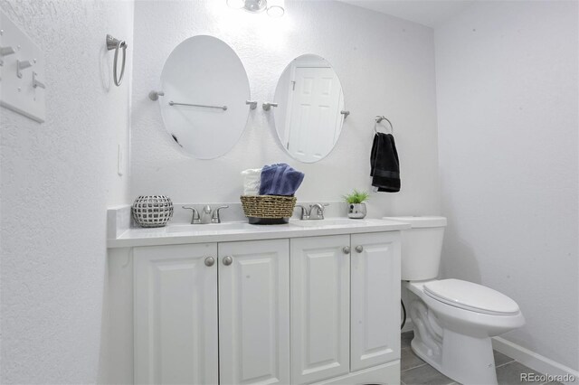 bathroom featuring toilet, double vanity, and a sink