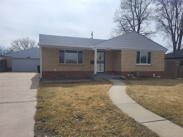 view of front of house with brick siding, roof with shingles, a front lawn, and an outbuilding