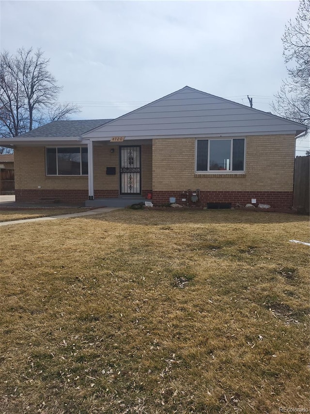 view of front of house with a front yard, brick siding, and fence