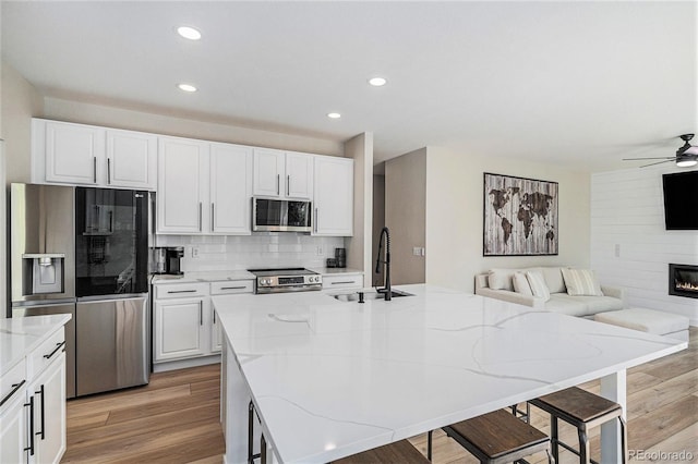 17174 E Rosebay Cir, Parker, CO 80134 - kitchen with stainless steel appliances, open floor plan, ceiling fan, backsplash, and light wood-style flooring