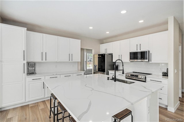 17174 E Rosebay Cir, Parker, CO 80134 - kitchen with stainless steel appliances, a kitchen breakfast bar, an island with sink, recessed lighting, and white cabinetry