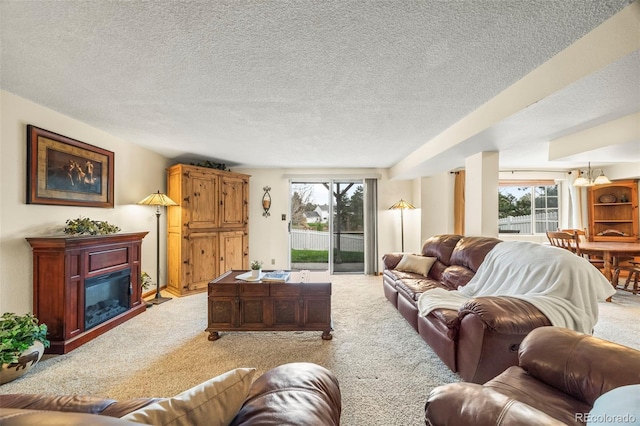 living area with a glass covered fireplace, a wealth of natural light, and light carpet