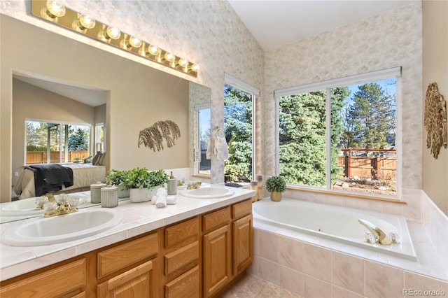 bathroom with double vanity, a tub with jets, ensuite bathroom, and a sink