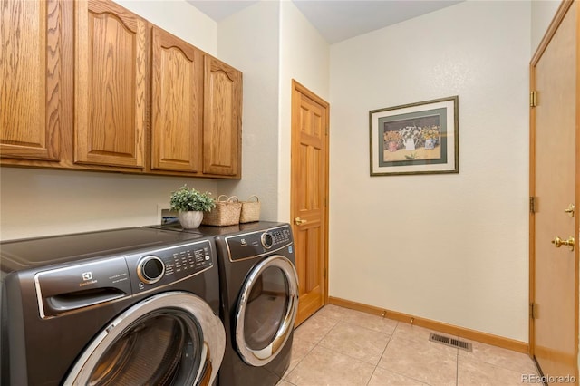 clothes washing area featuring light tile patterned floors, baseboards, visible vents, cabinet space, and washer and clothes dryer