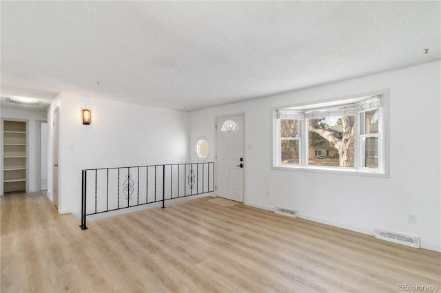 spare room with visible vents, a textured ceiling, and wood finished floors