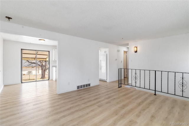 unfurnished room featuring visible vents, a textured ceiling, and wood finished floors