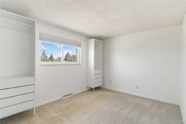 unfurnished bedroom featuring baseboards, carpet, visible vents, and a textured ceiling