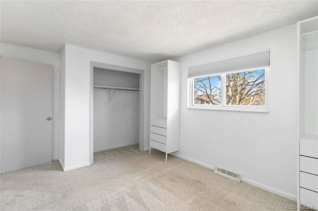 unfurnished bedroom with visible vents, a textured ceiling, a closet, carpet flooring, and baseboards