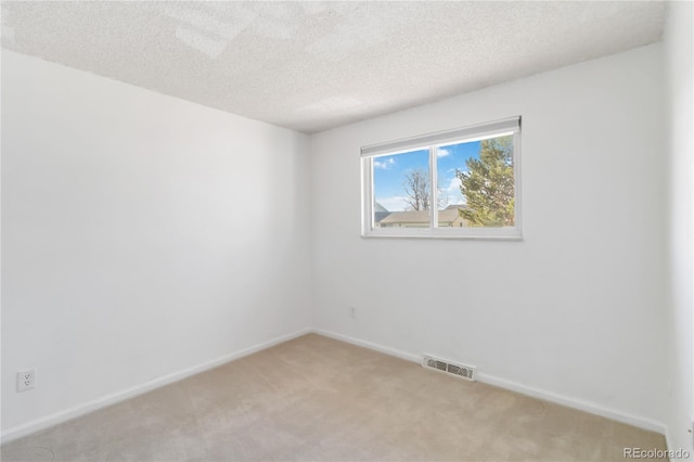 empty room with baseboards, light colored carpet, visible vents, and a textured ceiling