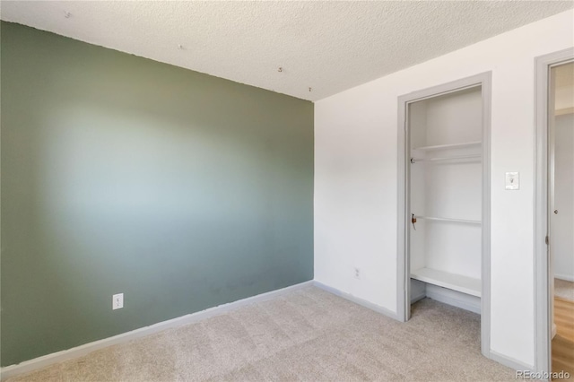 unfurnished bedroom featuring a spacious closet, baseboards, carpet, a closet, and a textured ceiling